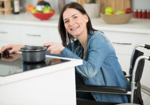 happy disabled woman in wheelchair cooking dinner