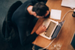 Blurred background of tired man working with laptop