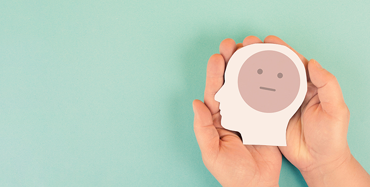 Two hands are holding a sad face.
