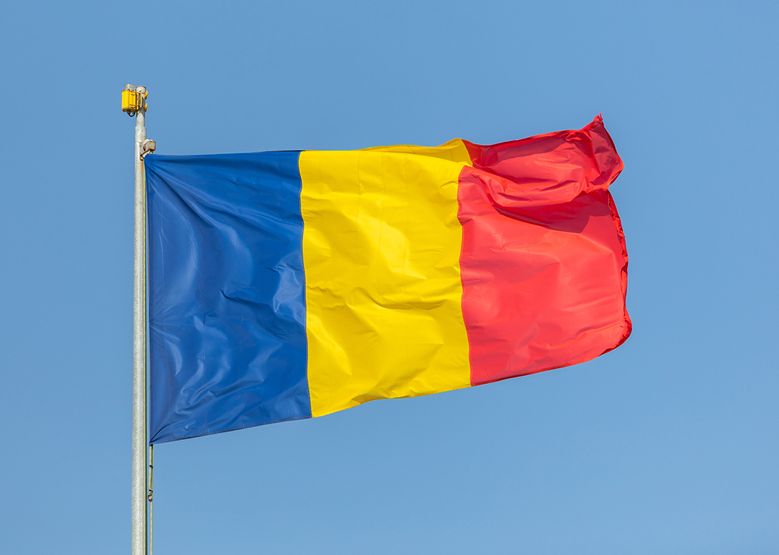 Romania flag waving against clean blue sky, close up
