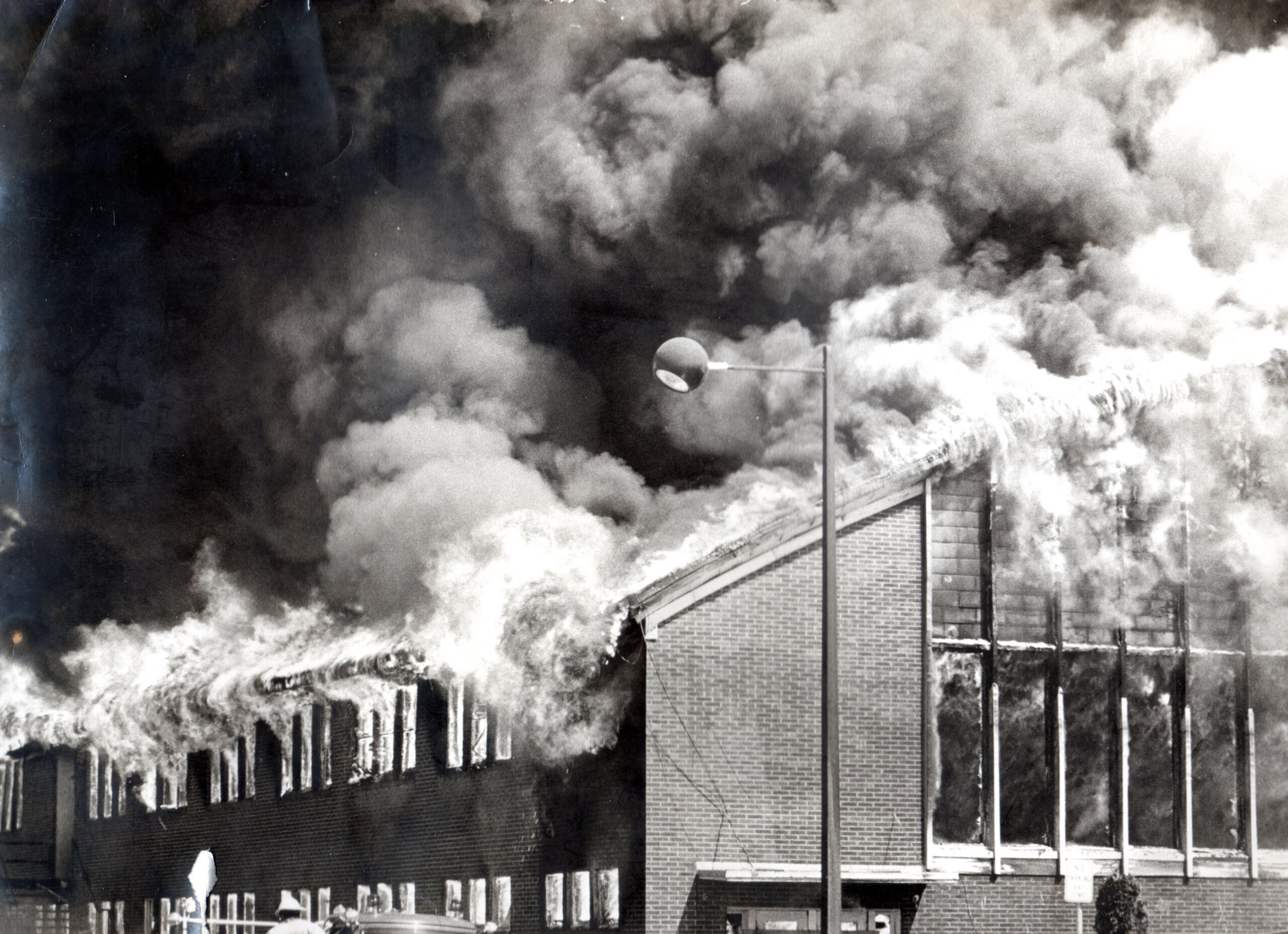 Smoke clouding in sky and fire blazing out of old building